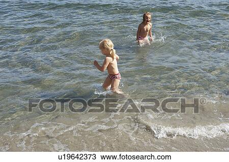 Children playing in waves on beach View Large Photo Image Stock Image - Children playing in waves on beach. Fotosearch