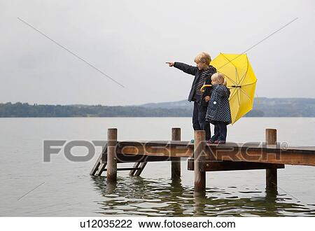 Children with yellow umbrella on dock View Large Photo Image Stock Image - Children with yellow umbrella on dock. Fotosearch