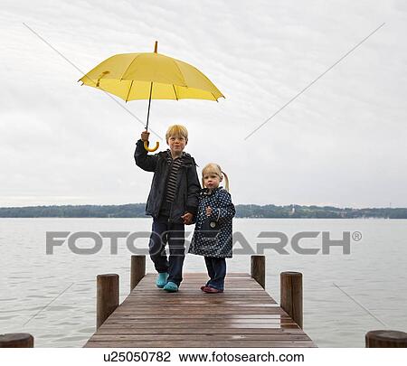 Children with yellow umbrella on dock View Large Photo Image Stock Image - Children with yellow umbrella on dock. Fotosearch