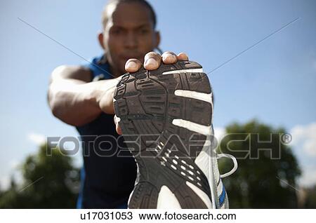 Stock Image - Close up of athlete stretching outdoors. Fotosearch