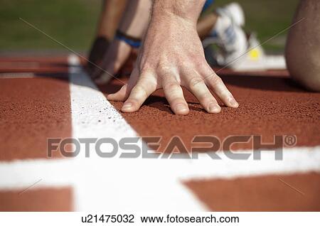 Stock Image - Close up of athlete's hand on track. Fotosearch