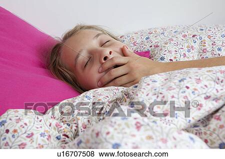 Close up of girl yawning in bed View Large Photo Image Stock Photo - Close up of girl yawning in bed. Fotosearch