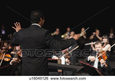 Conductor waving baton over orchestra View Large Photo Image Stock Photograph - Conductor waving baton over orchestra. Fotosearch