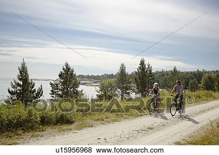 Couple bicycling on rural dirt path View Large Photo Image Stock Photo - Couple bicycling on rural dirt path. Fotosearch