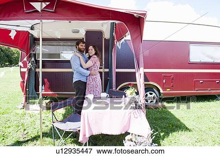 Stock Photo - Couple hugging outside trailer. Fotosearch