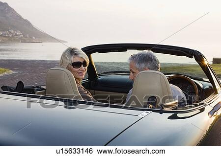 Couple in convertible admiring coastline View Large Photo Image Stock Photograph - Couple in convertible admiring coastline. Fotosearch