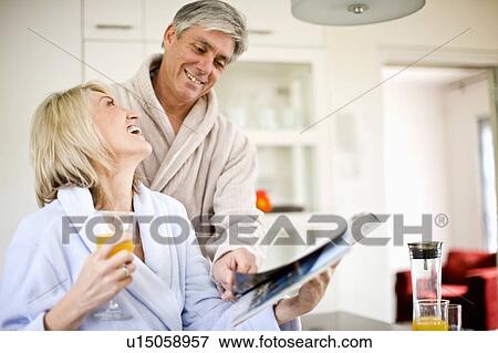 Couple reading magazine at breakfast View Large Photo Image Stock Photo - Couple reading magazine at breakfast. Fotosearch