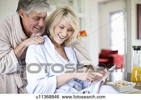 Stock Photograph - Couple reading magazine at breakfast. Fotosearch
