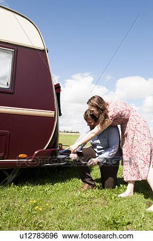Stock Photograph - Couple working on trailer in field. Fotosearch