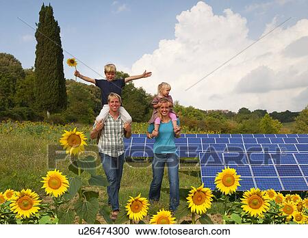 Stock Image - Family in field by solar panels. Fotosearch