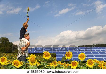 Stock Image - Father and son in field by solar panels. Fotosearch
