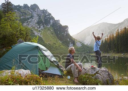 Stock Image - Father and son relaxing at campsite. Fotosearch