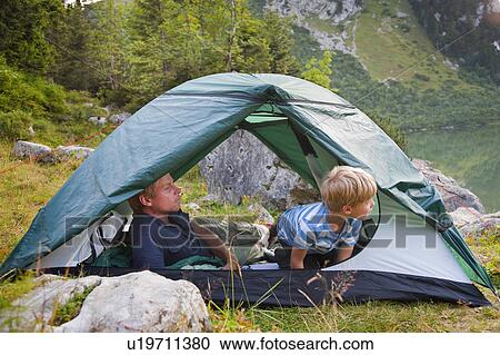Stock Image - Father and son relaxing in tent. Fotosearch