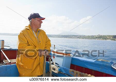 Picture - Fisherman reeling in nets on boat. Fotosearch