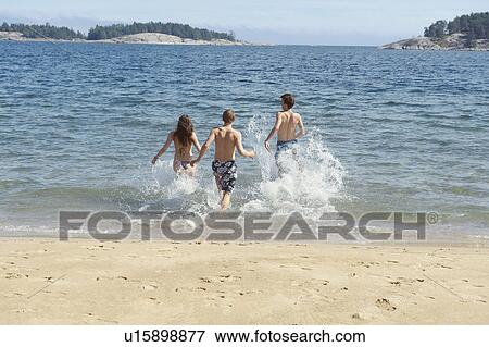 Friends running into ocean on beach View Large Photo Image Stock Photo - Friends running into ocean on beach. Fotosearch