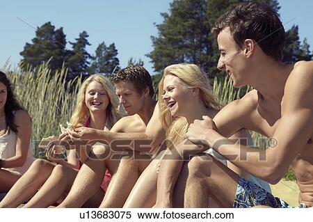 Stock Photography - Friends sitting together on beach. Fotosearch