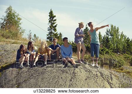 Stock Photography - Friends sitting together on boulder. Fotosearch