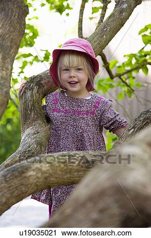 Stock Image - Girl climbing tree in forest. Fotosearch