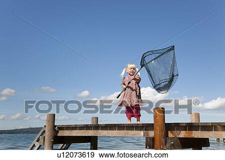 Stock Photo - Girl fishing with net in lake. Fotosearch