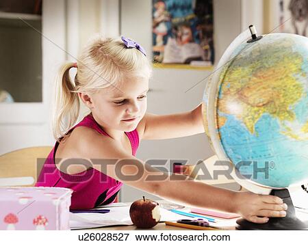 Girl holding globe at desk View Large Photo Image Stock Photo - Girl holding globe at desk. Fotosearch