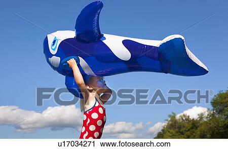 Stock Image - Girl holding inflatable whale outdoors. Fotosearch