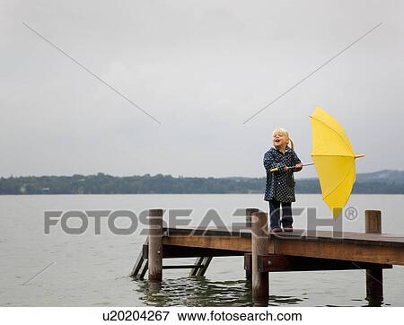 Girl holding yellow umbrella on dock View Large Photo Image Stock Photo - Girl holding yellow umbrella on dock. Fotosearch