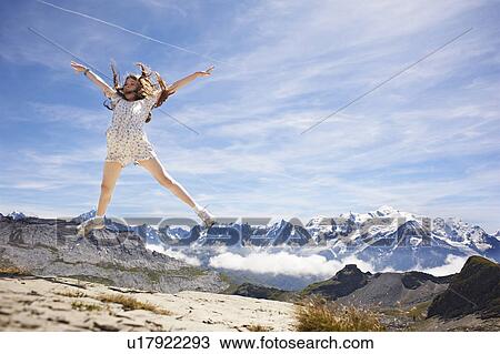 Stock Image - Girl jumping in rocky landscape. Fotosearch
