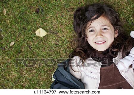 Stock Photo - Girl laying in grass outdoors. Fotosearch