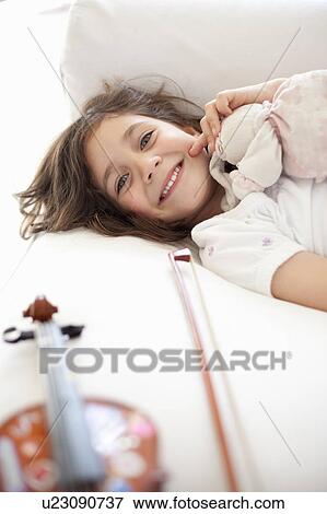 Stock Photo - Girl laying on couch with violin. Fotosearch