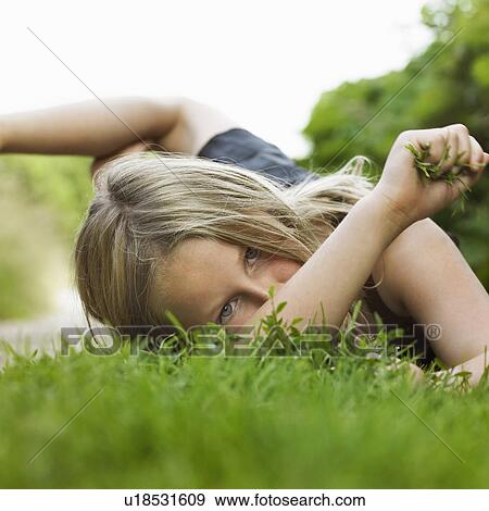 Stock Photo - Girl laying on grass in dirt path. Fotosearch