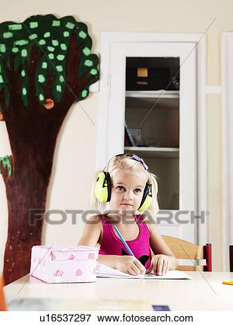 Girl listening to headphones at desk View Large Photo Image Stock Photo - Girl listening to headphones at desk. Fotosearch