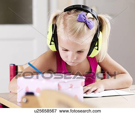 Stock Photo - Girl listening to headphones at desk. Fotosearch