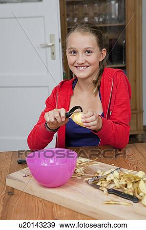 Girl peeling potatoes in kitchen View Large Photo Image Stock Photo - Girl peeling potatoes in kitchen. Fotosearch