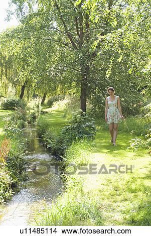 Picture - Girl picking flowers by river. Fotosearch