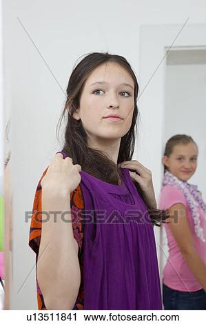 Stock Image - Girl picking outfits in bedroom. Fotosearch