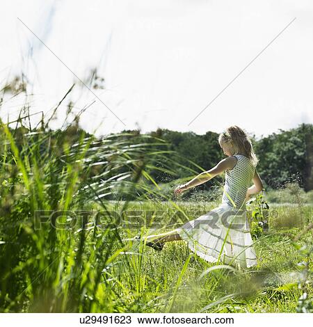 Girl playing in tall grass in field View Large Photo Image Stock Image - Girl playing in tall grass in field. Fotosearch