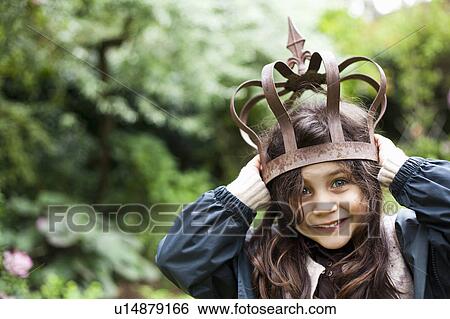 Stock Photograph - Girl playing with metal crown outdoors. Fotosearch