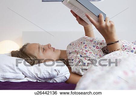 Stock Photograph - Girl reading in bed. Fotosearch
