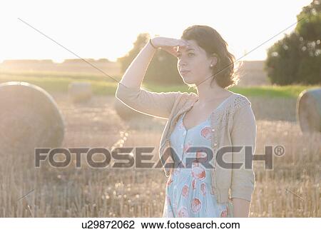 Girl shielding her eyes in hay field View Large Photo Image Stock Image - Girl shielding her eyes in hay field. Fotosearch