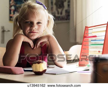 Girl sitting at desk with apple View Large Photo Image Stock Image - Girl sitting at desk with apple. Fotosearch