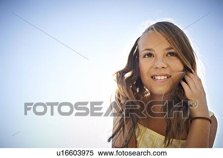 Stock Photography - Girl smiling against blue sky. Fotosearch