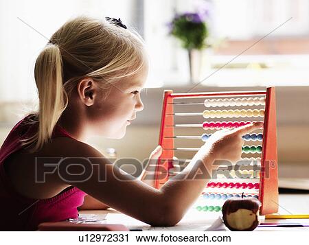 Stock Image - Girl using abacus at desk. Fotosearch