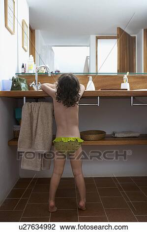 Stock Image - Girl washing her hands in bathroom. Fotosearch