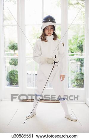 Stock Image - Girl wearing fencing gear in living room. Fotosearch