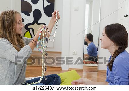 Stock Photo - Girls examining jewelry in bedroom. Fotosearch