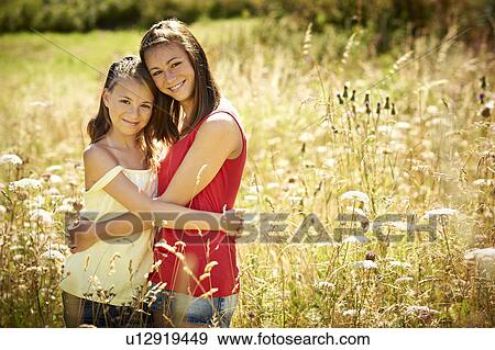 Stock Photo - Girls hugging in tall grass. Fotosearch