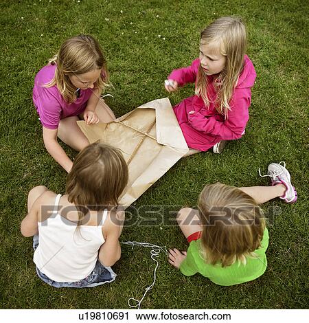 Girls making a kite in grass View Large Photo Image Stock Image - Girls making a kite in grass. Fotosearch