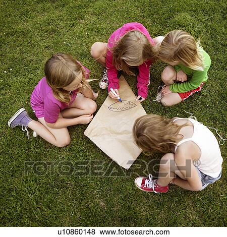 Girls making a kite in grass View Large Photo Image Stock Photo - Girls making a kite in grass. Fotosearch