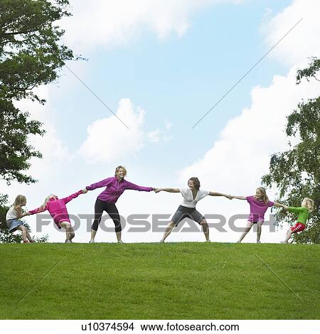 Picture - Girls playing tug-of-war in field. Fotosearch