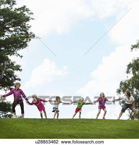 Girls playing tug-of-war in field View Large Photo Image Stock Image - Girls playing tug-of-war in field. Fotosearch